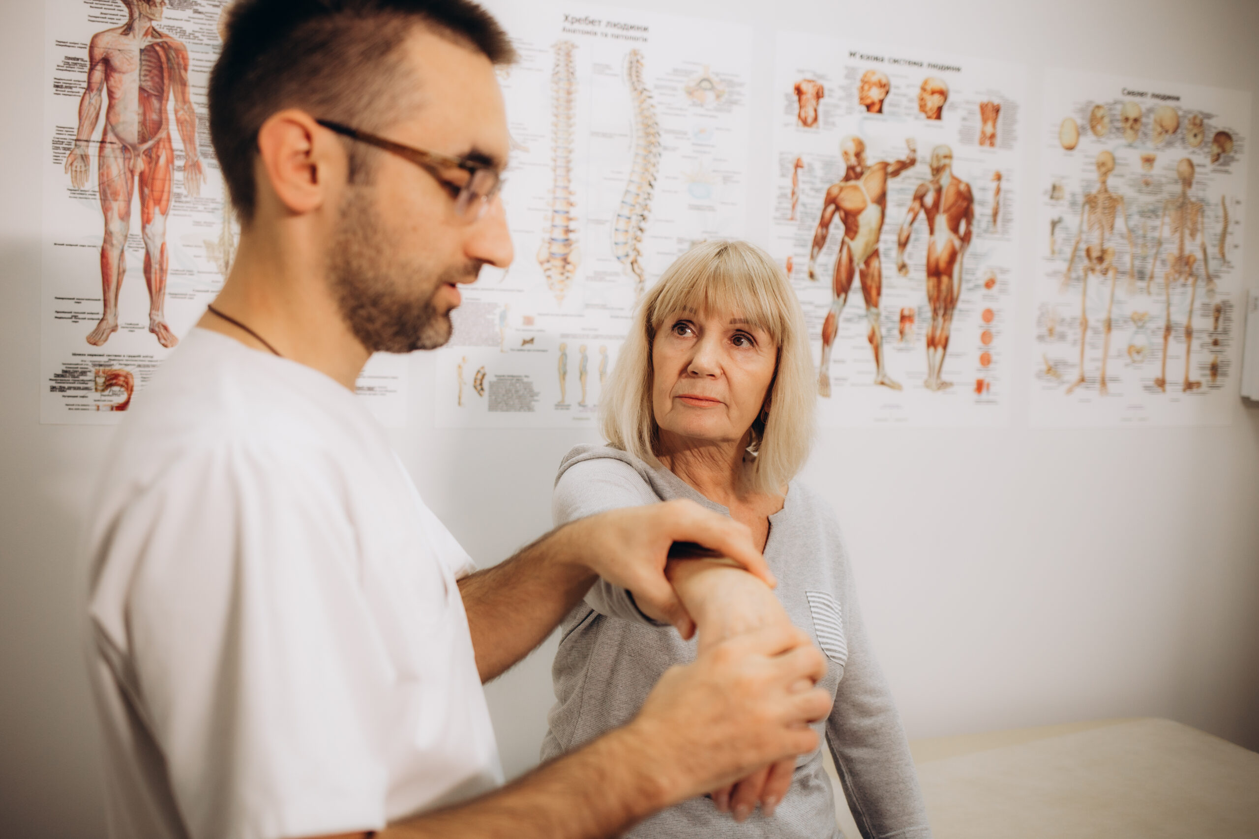 A professional masseur gives a senior female patient a massage, treating back pain